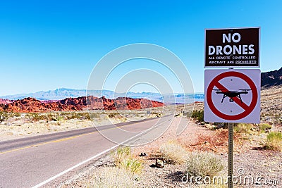 No drones zone warning sign prohibit the launching, landing, or operation of unmanned aircraft. Lonely road, scenic red sandstone Stock Photo