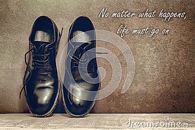 no matter what happens, life must go on, brown board and work shoes on wooden floor Stock Photo