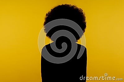 No name, anonymous hiding face in shadow, human identity. Silhouette portrait of curly hair person standing calm alone in darkness Stock Photo