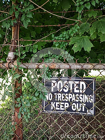 Grungy No Trespassing Sign on Rusty Chain Link Fence. Stock Photo