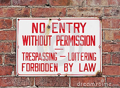 No trespassing sign mounted on brick wall Stock Photo