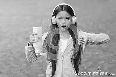 No water no life. Concerned child show thumbs down hand gesture. No water left in bottle. Thirsty girl wear headphones Stock Photo