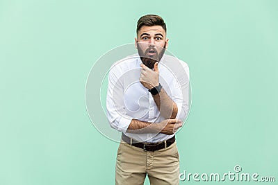 No way! Young adult with beard with shocked facial expression, holdings hands on chin. Stock Photo