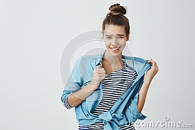 Nobody can criticize my style. Portrait of cool carefree european woman with bun hairstyle pulling denim shirt as if Stock Photo