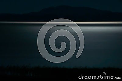 Scary, mystical landscape. Nocturnal lake with moonlight road. Blue night landscape with lake and moonlight. Stock Photo