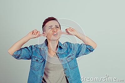 Noisy neighbors. Portrait of a boy alike woman girl plugging the ears looking up Stock Photo