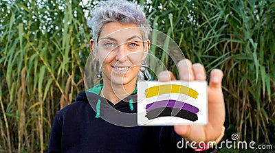 non-binary person claims gender identity with a non binary flag Stock Photo