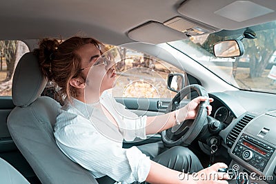 Non binary young driving a car with hand on the lever looking in the rear view mirror Stock Photo