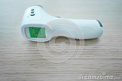 Non-contact infrared thermometer is the wooden table. On the green screen the figure numeral is 36.6 Stock Photo