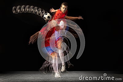 Non stop moving. Young caucasian football soccer player playing in motion in mixed light on dark background. Stock Photo