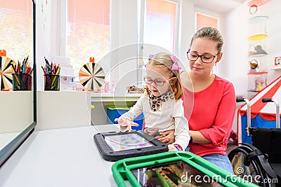 Non-verbal girl living with cerebral palsy, learning to use digital tablet device to communicate. Stock Photo