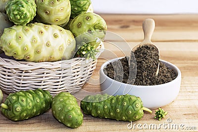 Noni fruit in basket with noni powder in ceramic bowl and wooden Stock Photo