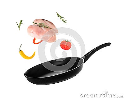 Nonstick frying pan with falling chicken fillet and vegetables on white background. Stock Photo