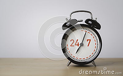 Nonstop Worldwide service available support concept , Number 24 hours and 7 days full-time contact to black alarm clock on wooden Stock Photo