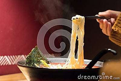 Noodle ramen on chopstick hold on women hand, food and drink concept with copy space Stock Photo