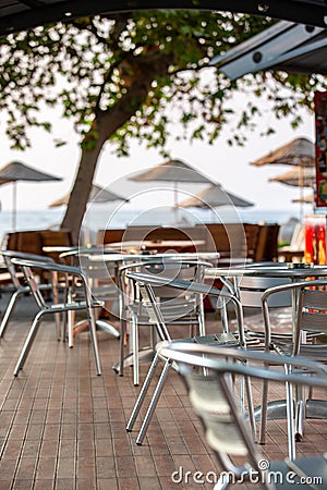 Nook of street cafee with several metal chairs and tables near sea. Stock Photo