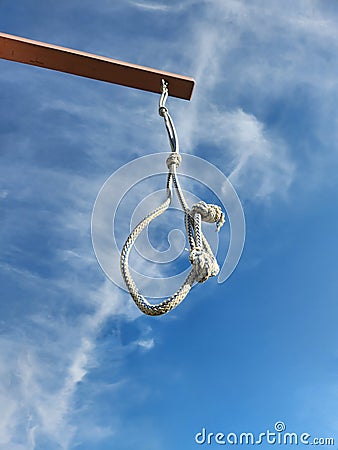 Noose from rope is suspended on gallows against blue sky with clouds Stock Photo