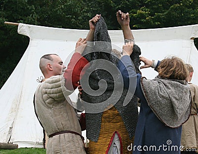 Norman soldiers dressing a soldiers with chain mail at the reenactment of The Battle of Hastings in the UK Editorial Stock Photo