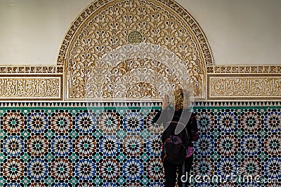 Morocco. Marrakesh. Madrasa Ben Youssef. The largest and most important madrassah in Morocco. A woman tourist look at the koranic Editorial Stock Photo