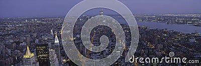 This is the north to south view of New York City from the Empire State Building. The lights of the skyscrapers are on as it dusk. Editorial Stock Photo