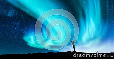 Northern lights and silhouette of a woman with raised up arms Stock Photo