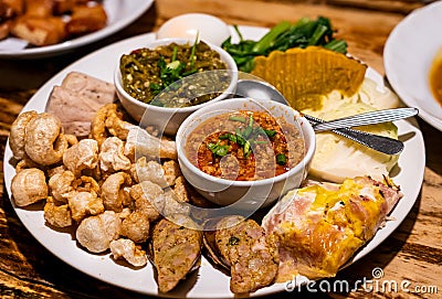 Northern Thai food starter plate - Thai sausage, pork rind and vegetable with red and green chili paste Stock Photo