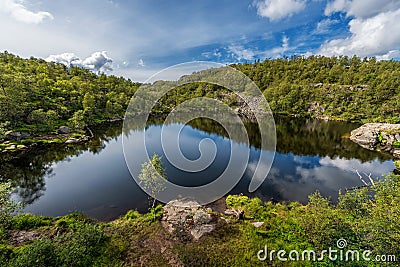 Norway Landscape. Close To Preikestolen Sightseeing Place. Mountain, Blue Sky. Reflection on Mountain Lake. Stock Photo