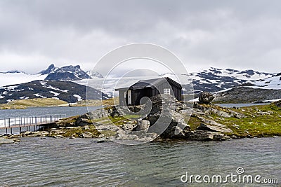 Norwegian black wooden house in the Nordic landscape by glacial lake Stock Photo