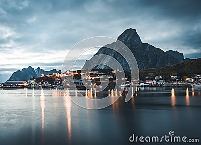 Norwegian fishing village Reine at the Lofoten Islands in Norway. Dramatic sunset clouds moving over steep mountain Editorial Stock Photo