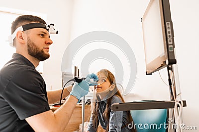 Nose endoscopy of child. Rhinoscopy procedure with rhinoscope. ENT doctor otolaryngologist with headlight treat nose kid Stock Photo