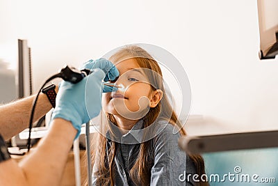 Nose endoscopy of child. Rhinoscopy procedure with rhinoscope. ENT doctor otolaryngologist with headlight treat nose kid Stock Photo