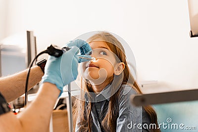 Nose endoscopy of child. Rhinoscopy procedure with rhinoscope. ENT doctor otolaryngologist with headlight treat nose kid Stock Photo