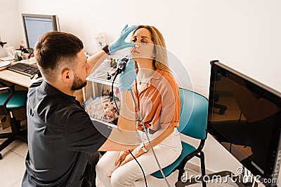 Nose endoscopy. Rhinoscopy procedure with rhinoscope. ENT doctor otolaryngologist with headlight treat nose woman Stock Photo