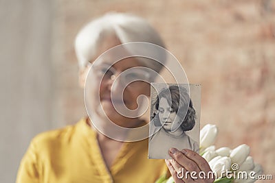 nostalgic photo of an old caucasian granny holding an old photo of her younger self Stock Photo