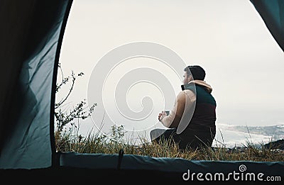 Not all classrooms have four walls. Rearview shot of a young man drinking coffee while camping in the wilderness. Stock Photo