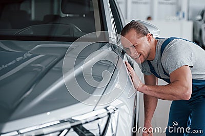 Not bad at all. After professional repairing. Man looking at perfectly polished silver colored car Stock Photo