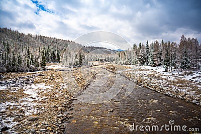 The not frozen bed of a beautiful winding Chibit River flowing through a snow-covered valley surrounded by mountains of Stock Photo