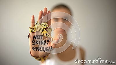 Not skinny enough written on woman palm with tape, severe diet, anorexia Stock Photo