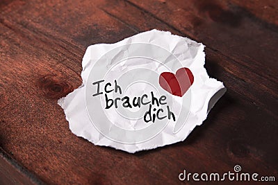 Note `Ich brauche dich` on torn slip of paper Stock Photo