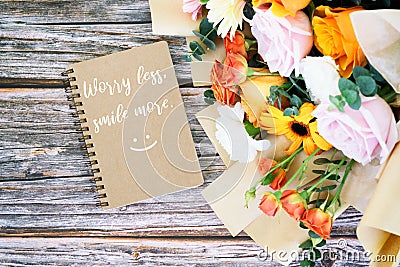 Note pad with text Worry less smile more with mixed flower bouquet Stock Photo