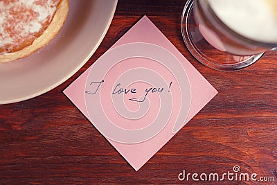 A note with the words `I love you` and a Cup of cappuccino on a wooden table Stock Photo