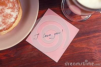 A note with the words `I love you` and a Cup of cappuccino Stock Photo