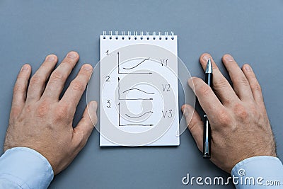 A notebook with charts of options of development of events and pen ready to be used. Male about to write in notebook Stock Photo