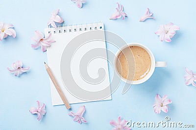 Notebook, cup of coffee and pink flowers on blue pastel background top view. Fashion woman working desk. Spring do list. Flat lay. Stock Photo