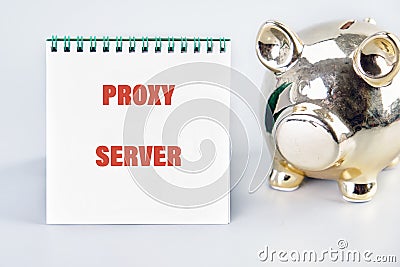 A notebook displays the words proxy server beside a shiny piggy bank, symbolizing financial security and technology Stock Photo