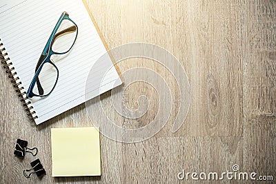 Notebook, eyeglasses and some stationery supplies on wood background Stock Photo