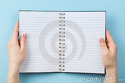 Notebook in female hands on blue background Stock Photo