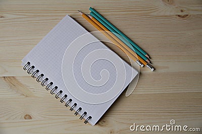 Notebook and four pencils next to the notebook on a light wooden table with copy space for text Stock Photo