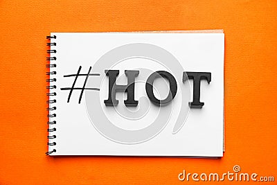 Notebook with hashtag HOT on color background Stock Photo