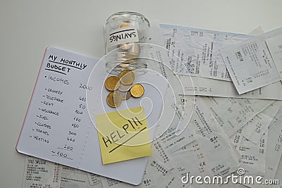 Notebook with month budget, receipts and coins, and ticket with `help` text. Stock Photo